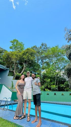 a group of three people standing next to a swimming pool at Green Hill Paradise Villa in Unawatuna