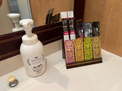 a white bottle of soap on a sink next to books at Hotel Karakonosato 唐比の里 in Isahaya