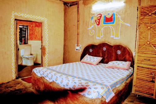 ein Schlafzimmer mit einem Bett mit einem Elefanten an der Wand in der Unterkunft Likhyani Permaculture Farm in Kūrāli