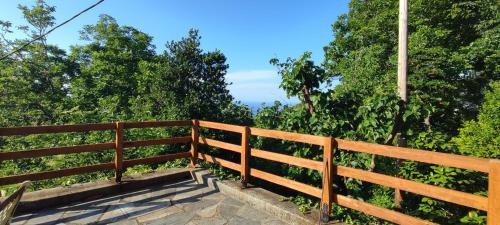 a wooden fence with a bench in front of trees at Venieri's Stone Villa in Tsagarada