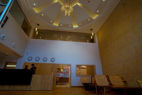 a lobby with a chandelier and tables and chairs at Beeza Clubhouse in Kottayam