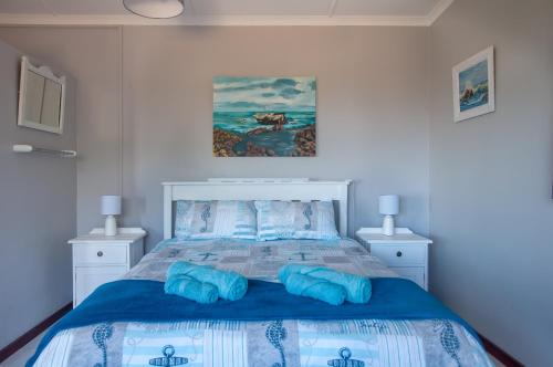 a bedroom with a large bed with blue pillows at À La Mer - Selfcatering Unit in Agulhas