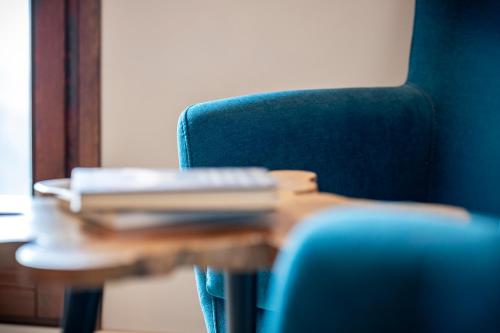 a blue chair and a table with books on it at Abbatissa Hotel Restaurant in Sant Joan de les Abadesses