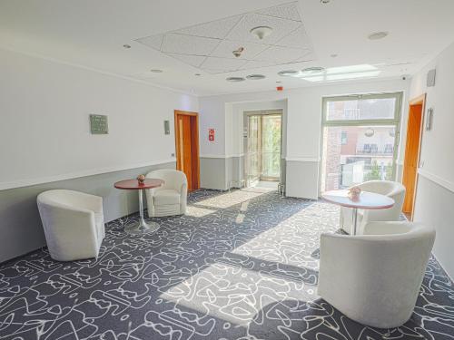 a waiting room with white chairs and tables and windows at Holiday Beach Budapest Wellness Hotel with Sauna Park in Budapest