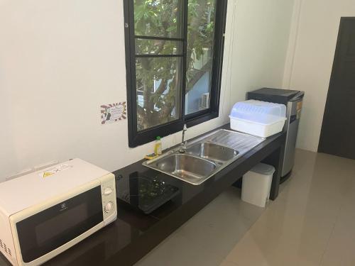 a kitchen counter with a sink and a microwave at Villa deux chambres avec piscine in Ao Nang