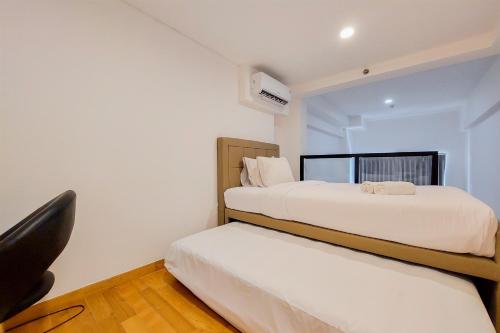 a bedroom with two beds and a chair at Spacious and Elegant Studio Loft Kingland Avenue Apartment By Travelio in Tangerang