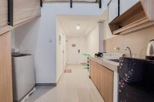 a kitchen with white walls and a long hallway at Spacious and Elegant Studio Loft Kingland Avenue Apartment By Travelio in Tangerang