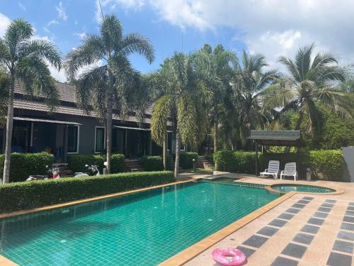 a swimming pool in front of a house with palm trees at Villa deux chambres avec piscine in Ao Nang