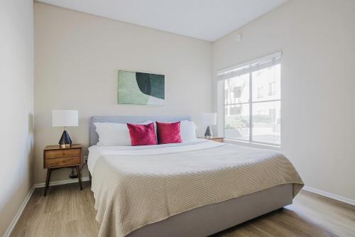 a white bedroom with a large bed with pink pillows at Blueground Burbank 1bd apartment LAX-1275 in Los Angeles