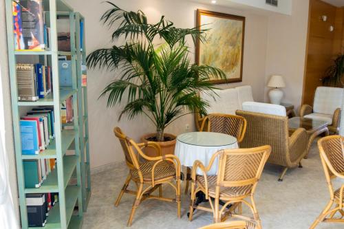 a table with chairs and a plant in a room at Aparthotel Villas La Manga in La Manga del Mar Menor
