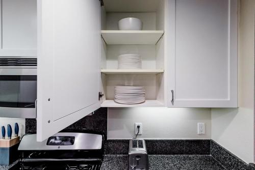 a kitchen with white cabinets and plates on shelves at Blueground Santa Clara 2bd apartment SFO-1771 in Milpitas