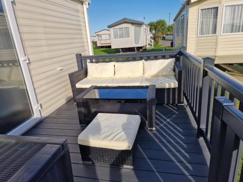 a deck with two chairs and a table and a bench at Seaside Holiday Home Inside a Resort in Selsey