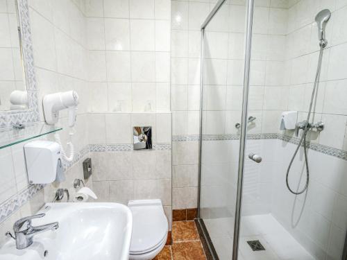 a bathroom with a shower and a toilet and a sink at Holiday Beach Budapest Wellness Hotel with Sauna Park in Budapest