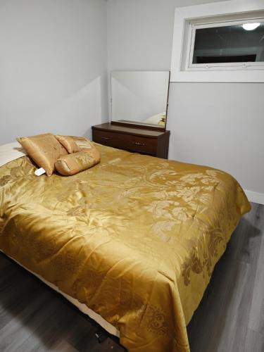 a bedroom with a gold bed with a dresser and a mirror at Chamber Inn in Edmonton