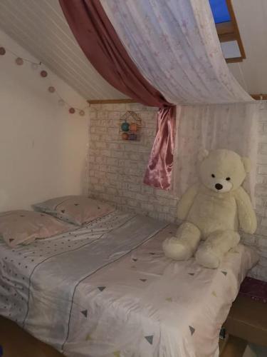 - un ours en peluche assis sur un lit dans une chambre dans l'établissement Agréable Duplex de type F4, à Sevran