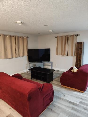 a living room with a red couch and a flat screen tv at Chamber Inn in Edmonton