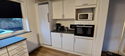 a kitchen with white cabinets and a microwave at Venos Home 2 in Lemvig