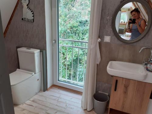 a woman taking a picture of a bathroom with a mirror at Ferienhaus Katharina - Urlaub Unter den Klippen in Lügde
