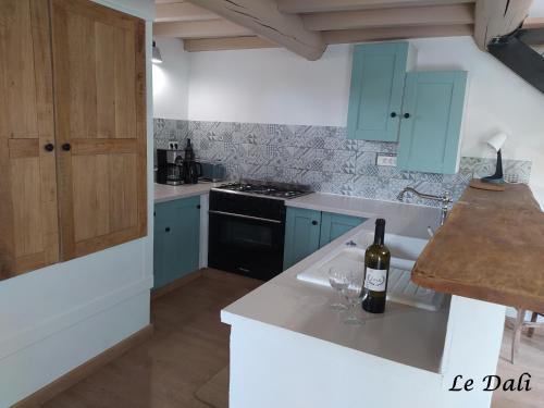 - une cuisine avec des placards bleus et une bouteille de vin sur un comptoir dans l'établissement Maison paisible Le Dali, à Piolenc