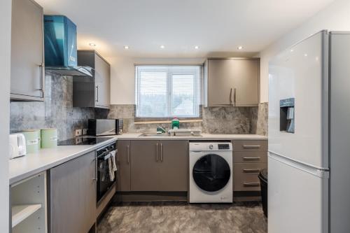 a kitchen with a washer and dryer at Ace Place - Pool Table - Etihad - Opposite Train Station in Moston