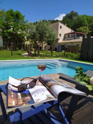 - une table avec un verre de vin à côté de la piscine dans l'établissement Maison paisible Le Dali, à Piolenc
