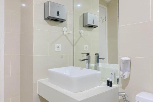 a white bathroom with a sink and a mirror at Brand New and Modern 2BR at Daan Mogot City Apartment By Travelio in Jakarta
