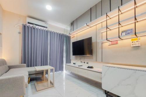 a living room with a couch and a tv at Elegant and Strategic 2BR Sky House BSD Apartment near ICE BSD By Travelio in Tangerang
