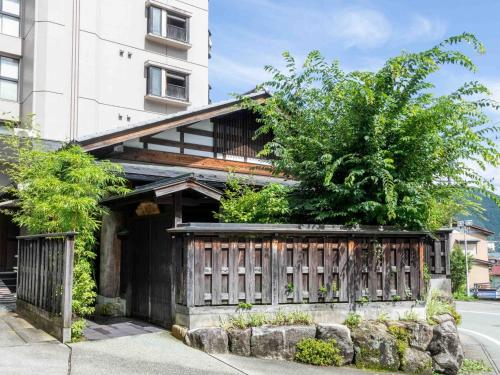 a house with a wooden fence in front of a building at Sasara in Gero