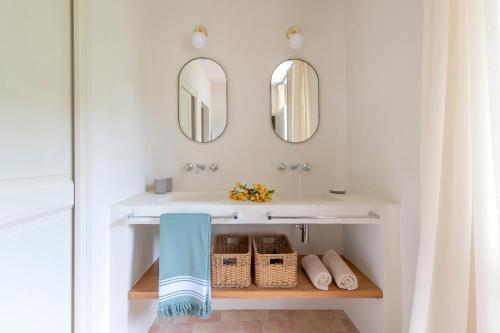 une salle de bain avec un lavabo et deux miroirs dans l'établissement Mas rénové dans un vignoble, à Saint-Étienne-du-Grès