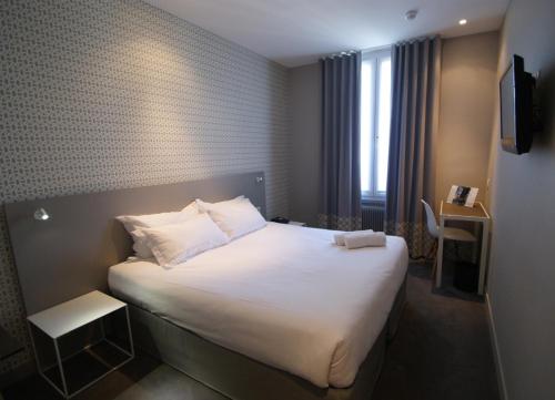 a hotel room with a large bed with white sheets at Parici Hôtel Boulogne Billancourt in Boulogne-Billancourt