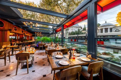 een restaurant met tafels en stoelen en grote ramen bij AHC Ayasofya Hotel - Special Class in Istanbul