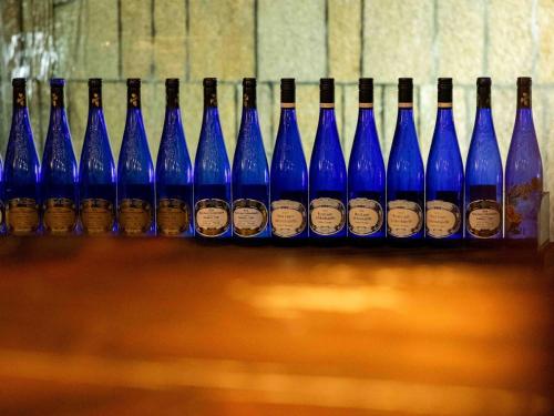 a row of blue wine bottles sitting on a shelf at Sasara in Gero