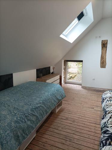 une chambre avec un lit et une lucarne dans l'établissement Gite Le Nymphéa, La Cambre, à Saint-Aubert-sur-Orne