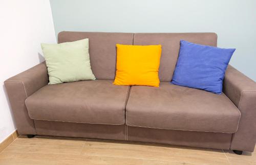 a brown couch with three colorful pillows on it at Home Sweet Home da Viky in Bari