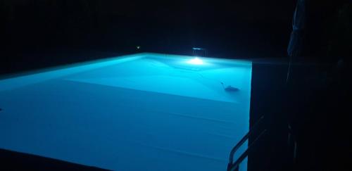 a blue swimming pool with a light in the dark at Alto Locandieri in Montebagnolo