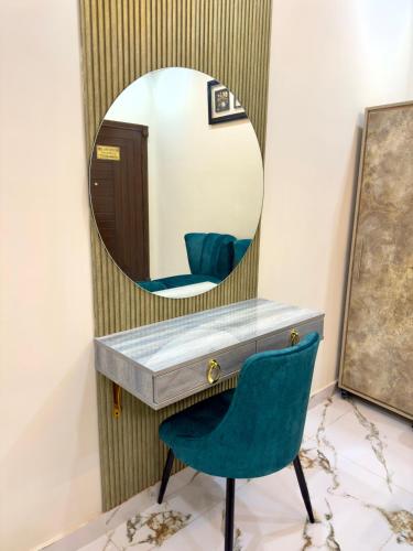 a mirror above a vanity with a green chair at Hotel Supreme Lahore in Lahore