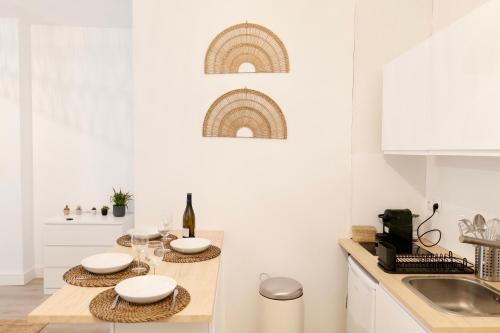 une cuisine avec des murs blancs et une table avec des assiettes et des verres dans l'établissement Le Fongate, à Marseille