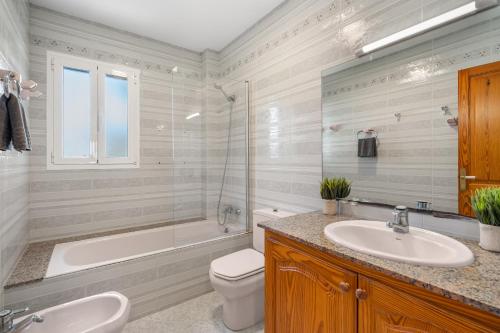 a bathroom with a tub and a toilet and a sink at Villa Cristina in Cala Blanca