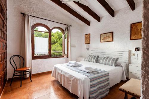 a white bedroom with a bed and a window at Villa Can Biel by Escape Home in Cala Morell