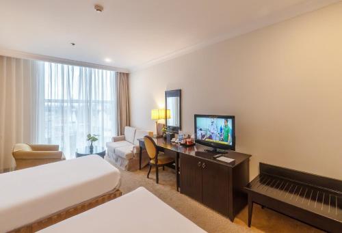 a hotel room with a bed and a desk with a television at La Sapinette Hotel Dalat in Da Lat