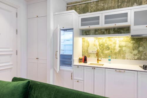 a kitchen with white cabinets and a green couch at Liberty Residence in Istanbul