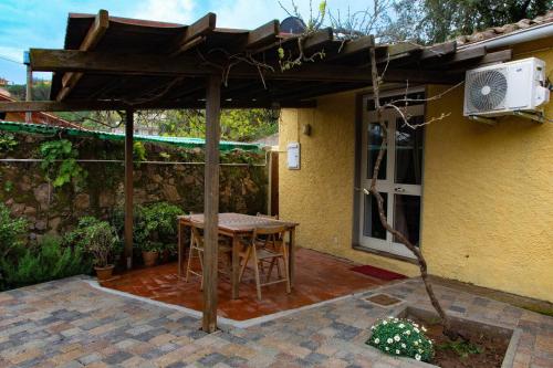 a patio with a table and an umbrella at Monolocale con veranda e giardino a Rio Marina in Rio Marina