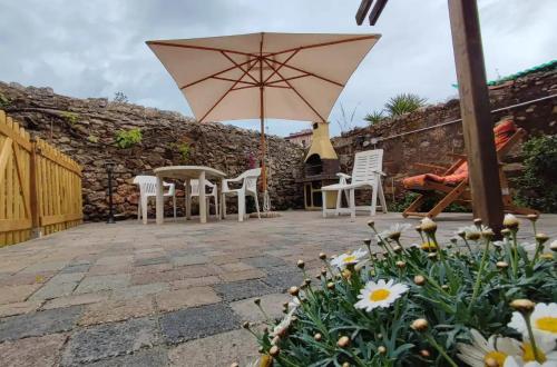 a patio with an umbrella and chairs and flowers at Monolocale con veranda e giardino a Rio Marina in Rio Marina