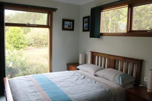 a bedroom with a bed and a large window at Eagle's Roost Farmstay B&B in Rocky Cape