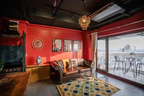 a living room with a couch and a red wall at Best river view - Loft apartment in great location in Bangkok