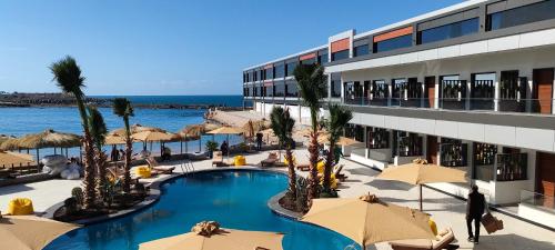 a resort with a swimming pool with umbrellas and the ocean at XU San Stefano Hotel Alexandria in Alexandria