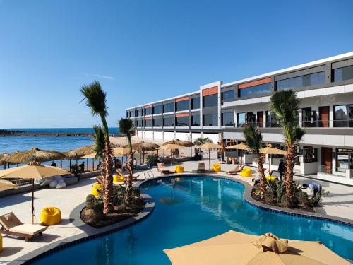 a resort with a swimming pool with umbrellas and the ocean at XU San Stefano Hotel Alexandria in Alexandria