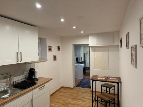 EglingにあるFerienwohnung Grafの白いキャビネットと小さなテーブル付きのキッチンが備わります。