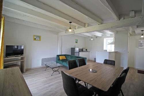 a living room with a table and a green couch at Gîte Les Champs N°5 in Saint-Mathieu