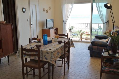 - un salon avec une table et des chaises offrant une vue sur l'océan dans l'établissement Face à la mer appartement T2 dans résidence avec parking - 5SOL16, à Saint Cyprien Plage